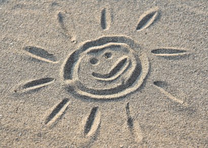 Lachende zon getekend in het zand